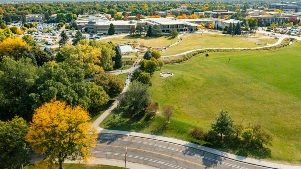 Aerial photo of sweeping green grass landscape surrounded by trees and winding sidewalks and roads