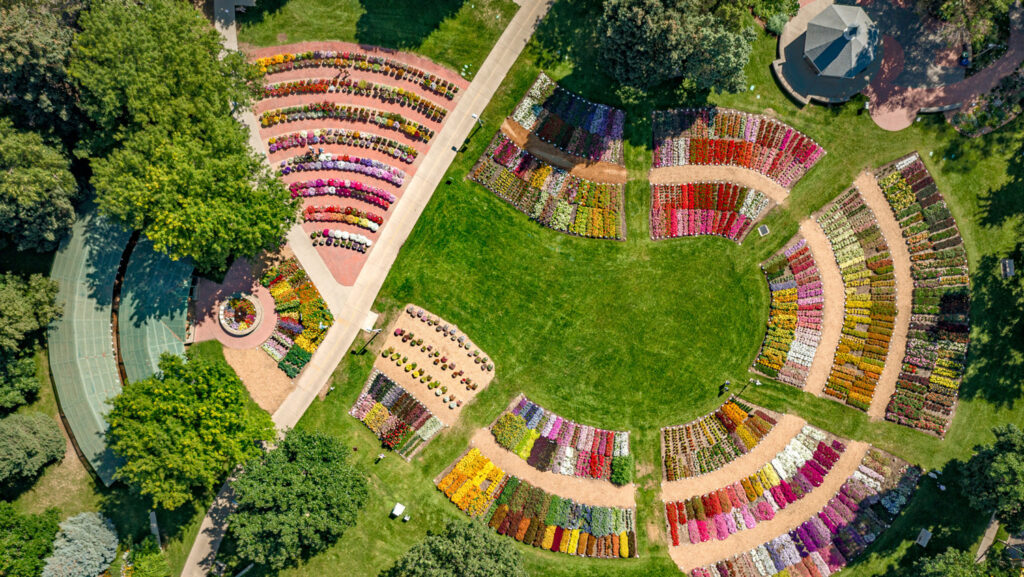 Aerial view of the trial garden. There are dozens of circular rows in bright colors amid green grass and trees