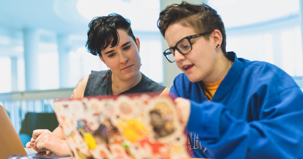 a student tutors another in the library