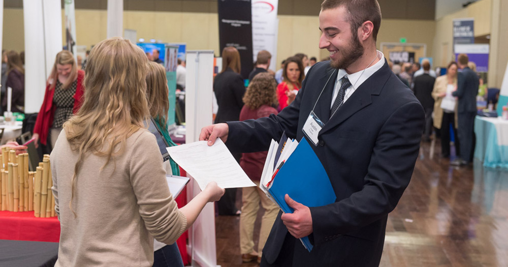 a student passes out a resume at a job fair