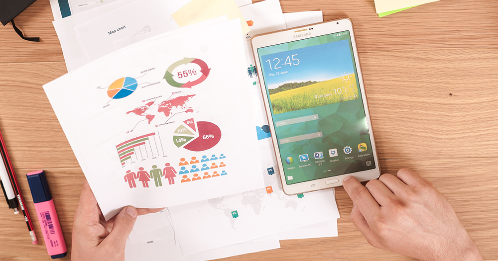 papers with statistics and graphs, a smartphone, and pens atop a desk