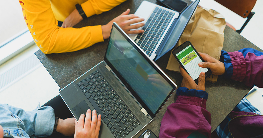 students work on computers and phones