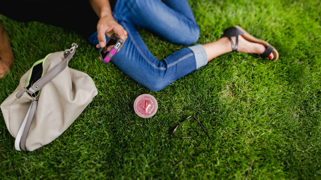 Aerial shot of a girl sitting on the grass looking at her phone.
