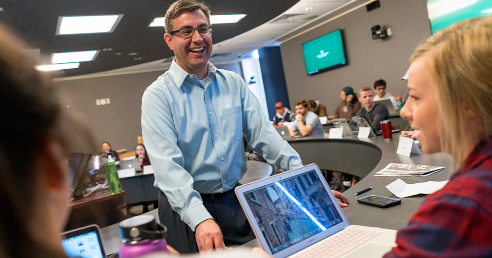 a teacher laughs with a student in a marketing class