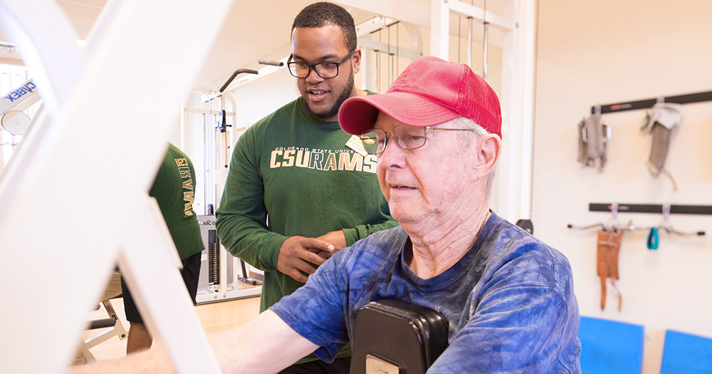 a student helps an elderly man in a physical therapy session