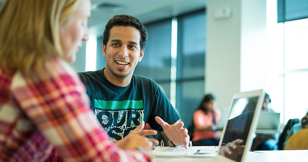 two students discuss over a laptop