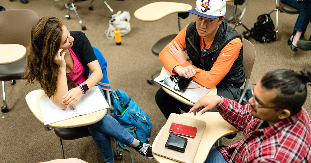 Econ students discuss in a casual classroom group setting