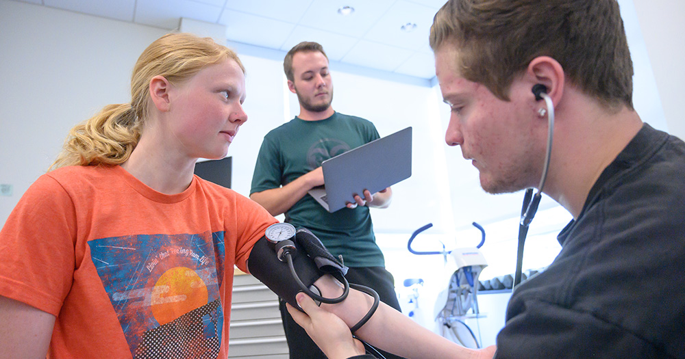 A health and exercise student takes the blood pressure of a community member.