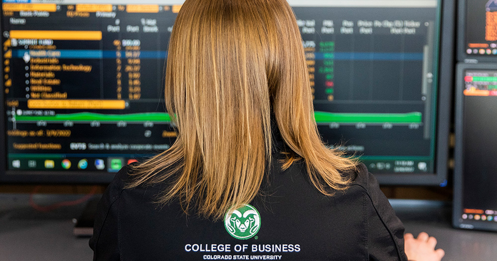 View of the back of a woman who is looking at screens with stock data