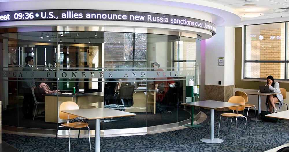 Exterior shot of data center with glass walls and scrolling stock market data around the top