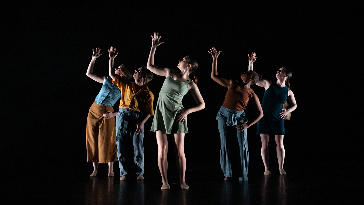 Students perform dance on a dramatically lit stage