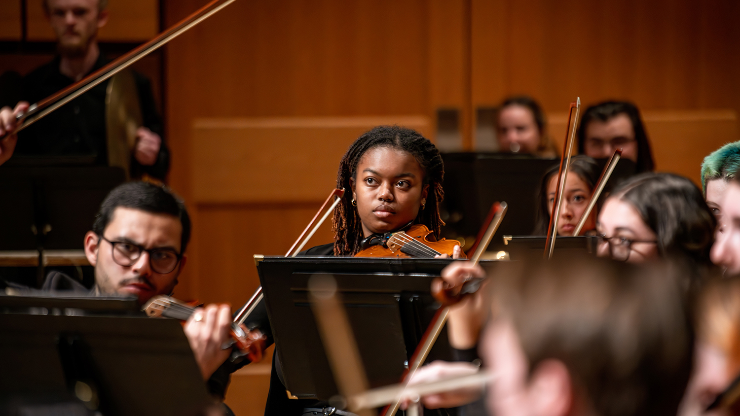 Orchestra students play violins during a CSU performance on stage