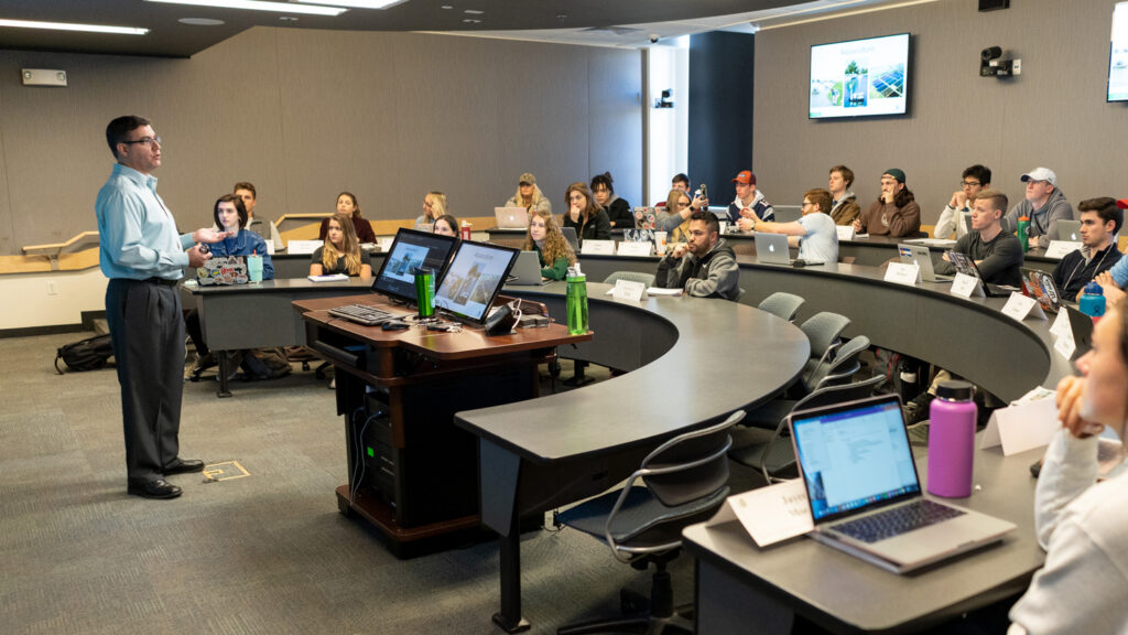 Students sit in a semicircle tables in classroom