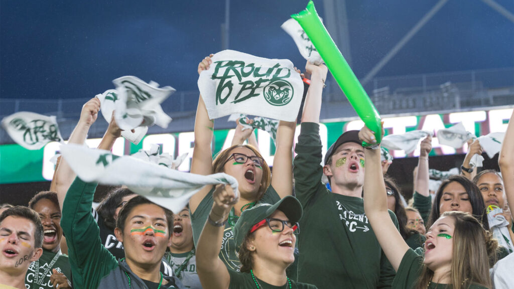 Student cheering on the Rams at a football game.