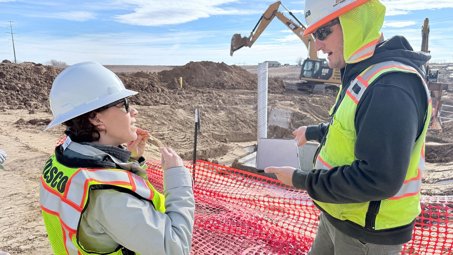 A student and professor work in hardhats on a jobsite