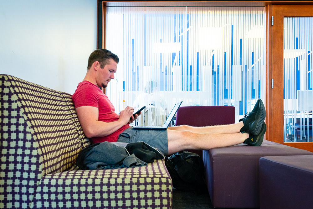 Student at the William E. Morgan Library studies on a funky couch with a frosted glass wall in the background