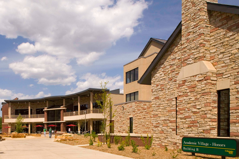 Blond brick building with multiple levels and umbrella-covered seating outside