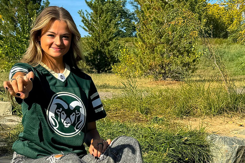 Student wearing CSU jersey holds up "rams horn" sign with her hands
