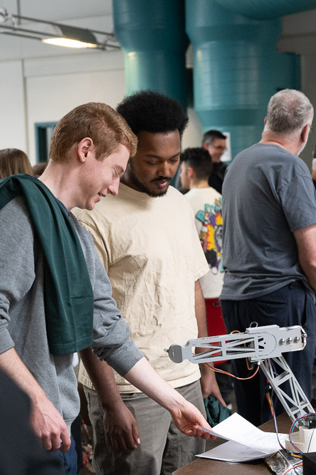 Two students look at a robotic arm