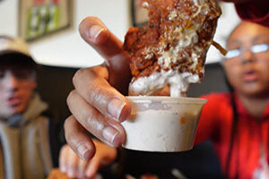 students dip chicken into sauce