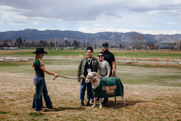 A family poses with a ram during a visit to CSU