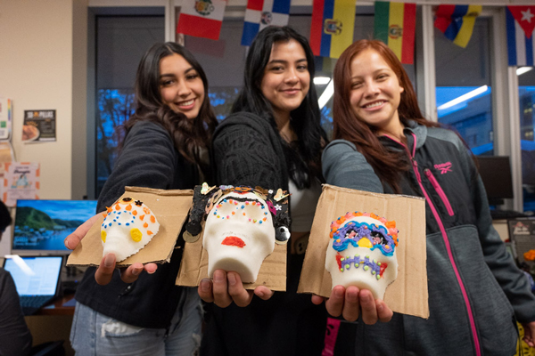 Students hold up sugar skulls they decorated with El Centro