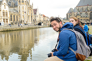 students sit on a canal in europe
