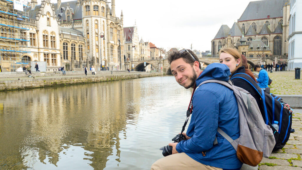 students sit on a canal in europe