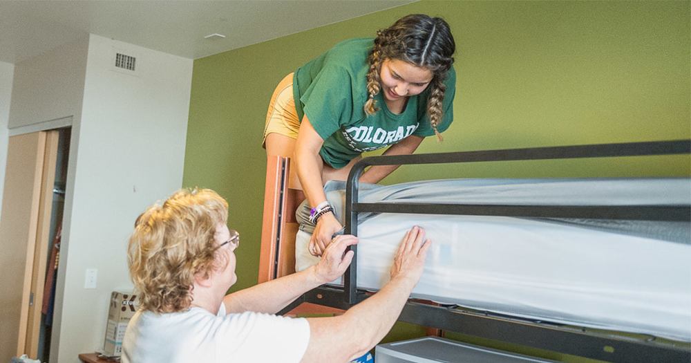 Parent helping student make bunk bed in dorm