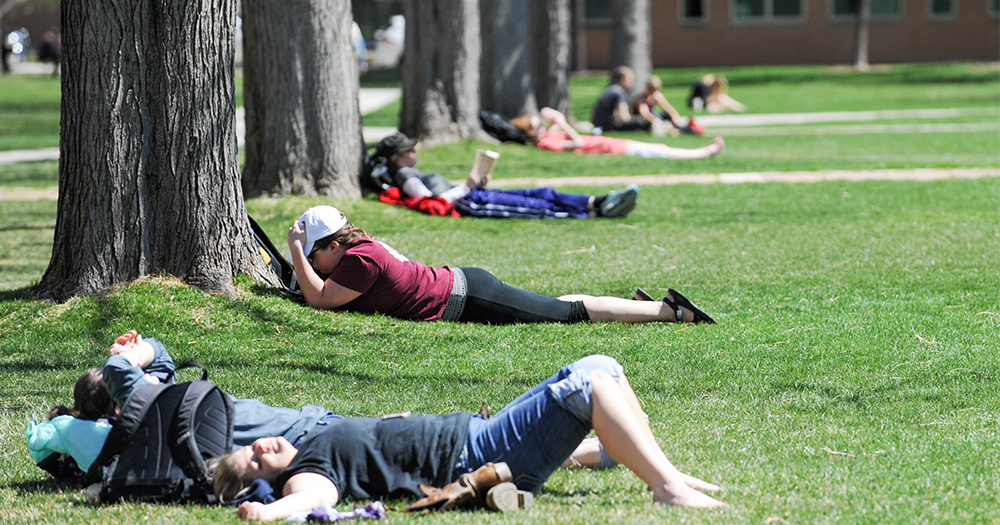 students laying on the grass in the oval