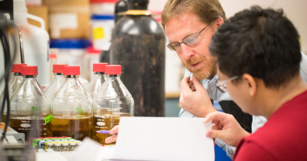 A chemistry professor conducts research with a student.