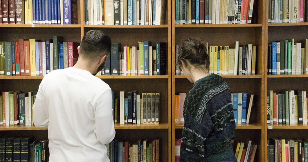 students browsing a wall of books