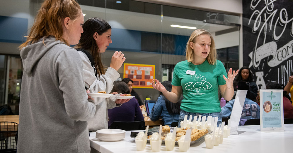 A student speaks with event attendees in a dining hall