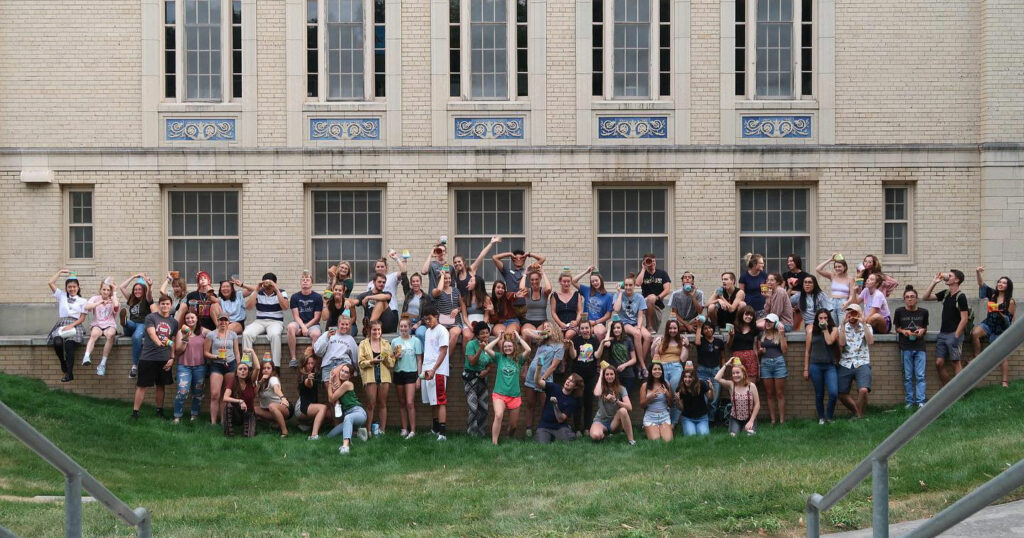 A large group of students pose in a lawn outside