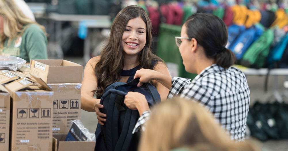 Student helping fill backpacks with supplies