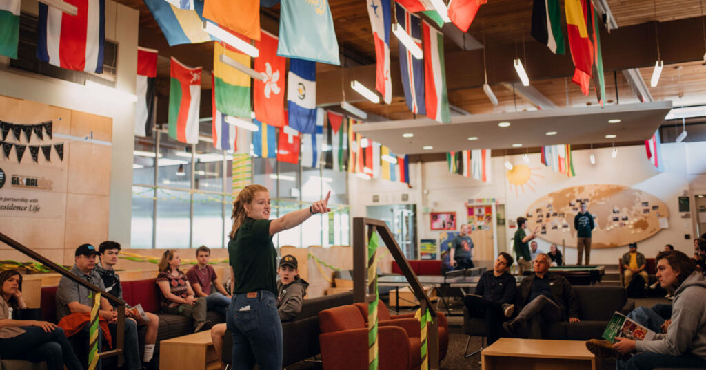 A tour guide points at features of a residence hall common space.