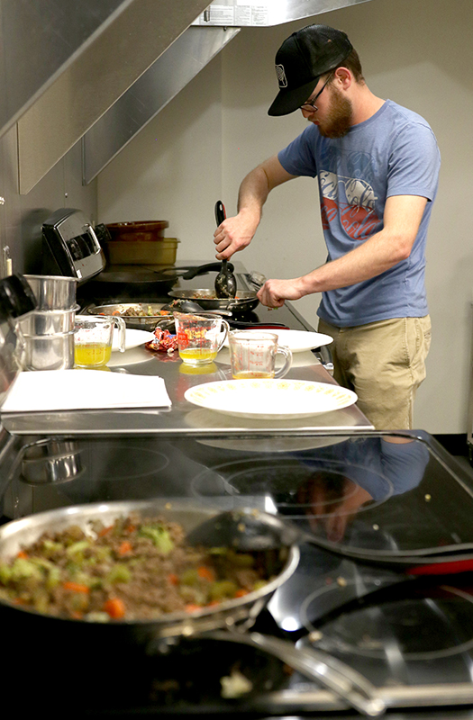 A student cooks on several stoves and prep spaces at once