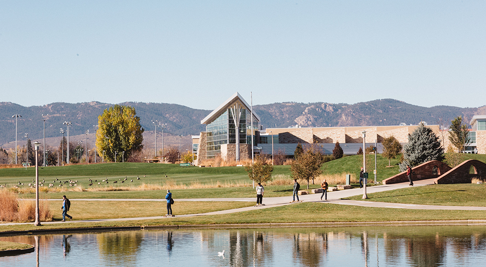 A small lagoon, green space and the CSU Rec Center are seen with mountain foothills in the background.