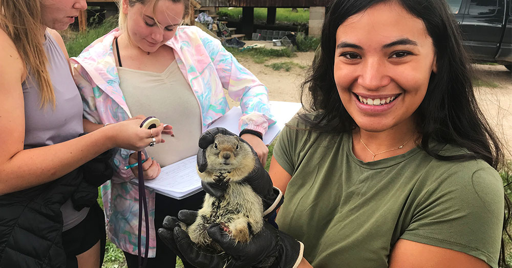A zoology student holds a live gopher, studying animal behavior in a field class