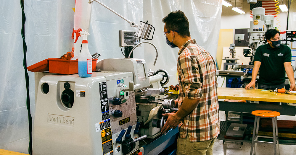 A student works on a high-tech digital machine to create metal parts