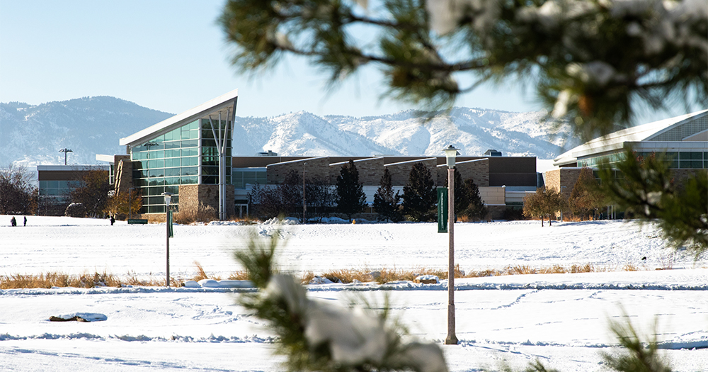 The snowcapped foothills of the Rocky Mountains rest behind a snow-covered field at Colorado State.