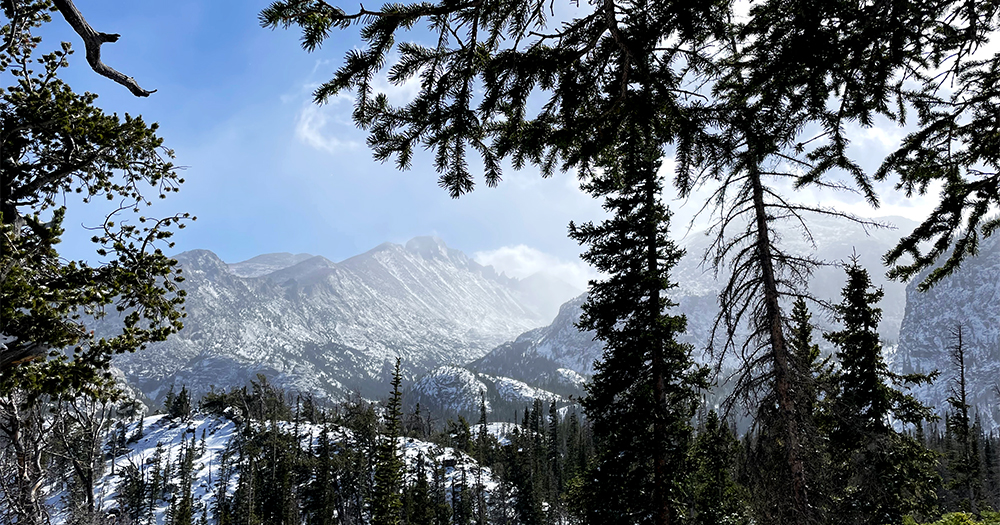 A wintery scene in Rocky Mountain National Park is seen through a break in the evergreen forest.