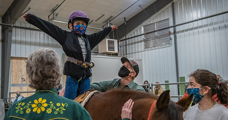 A young boy sits atop a horse during an equine therapy session at Colorado State.