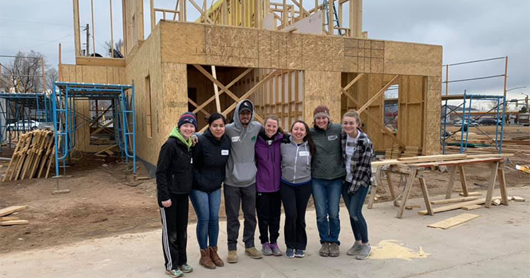 Members of Habitat for Humanity CSU pose for a group photo in front of a home build in progress.