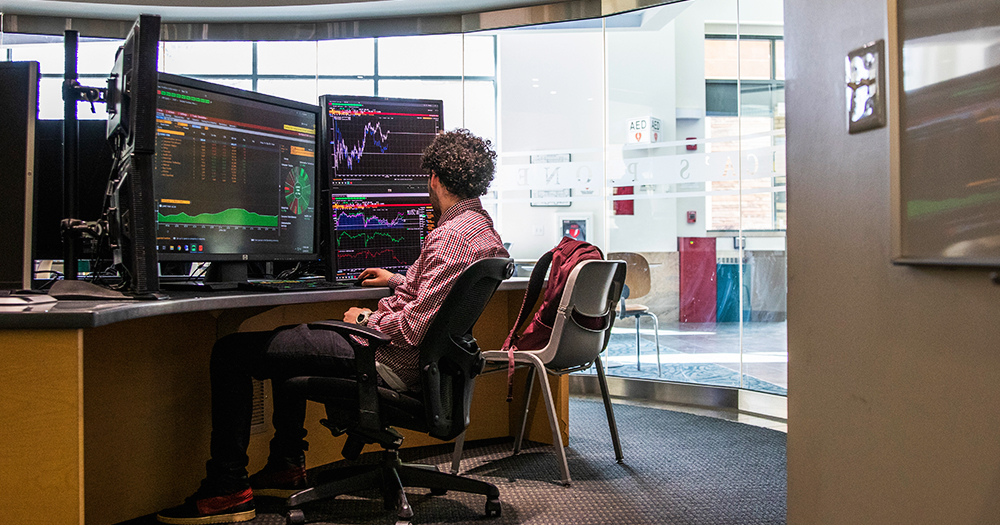 A student relaxes in his chair as he watches stock prices in the data lab