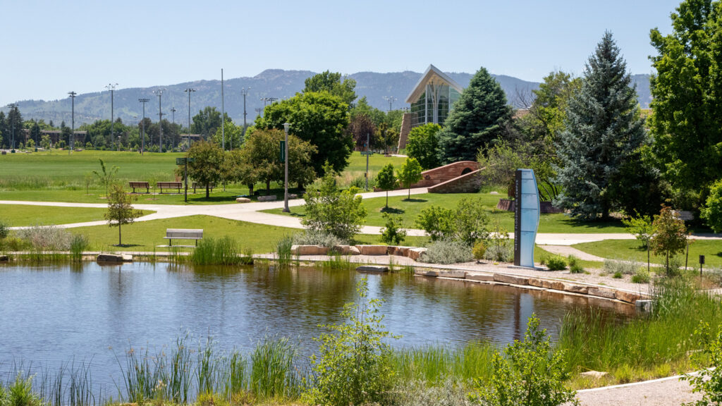 Foothills in background with campus building, footbridge, and pond in foreground