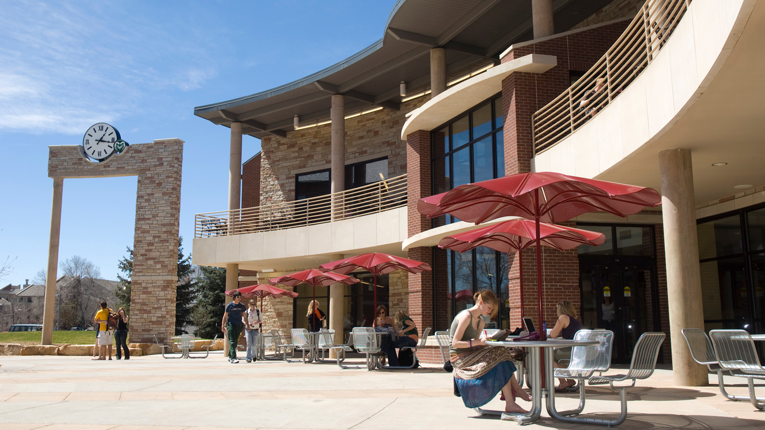 People study at tables and walk around outside residence hall