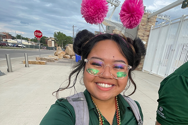 Cindy wearing CSU gear and pink pom poms on her head