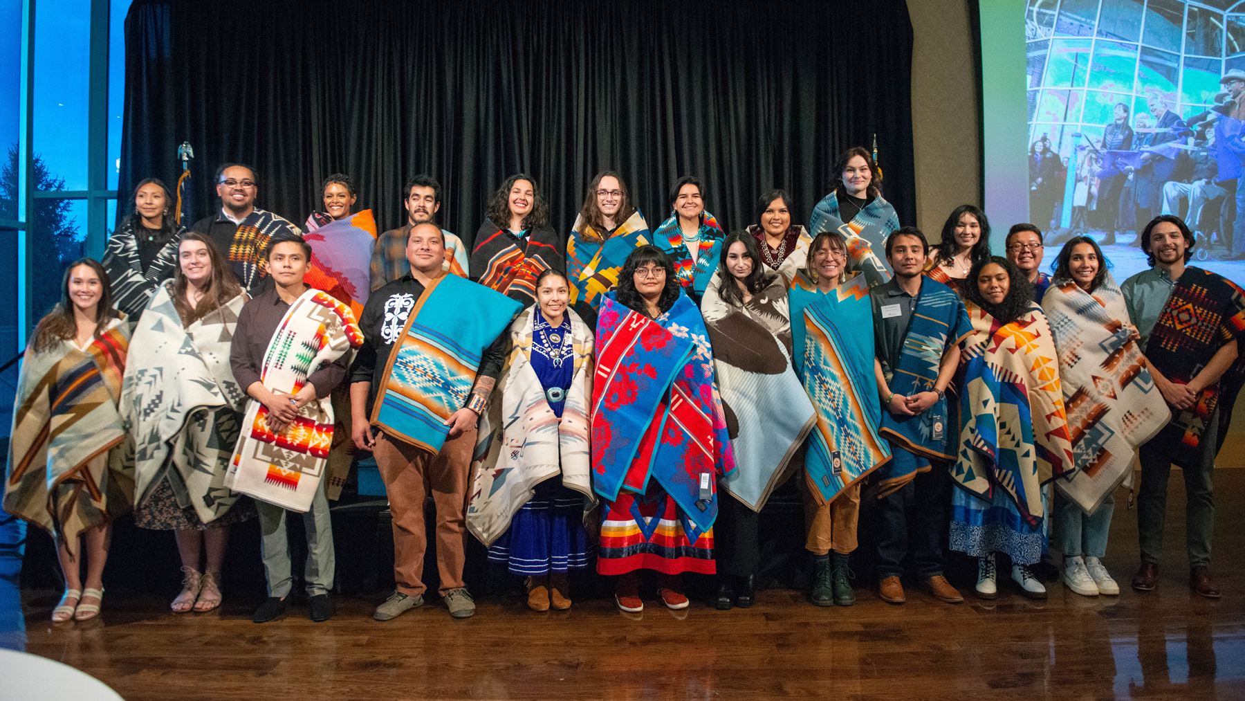 Native American students pose for a group photo with their traditional blankets