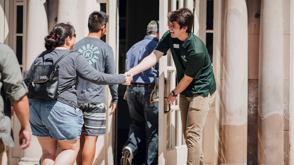 A student shakes hands with visitors.